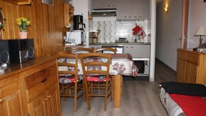 A compact kitchen with wooden cabinets, a dining table with chairs, a microwave, and a small refrigerator. - Holidays close to the slopes. Pra-Loup 1600 (Uvernet-Fours)