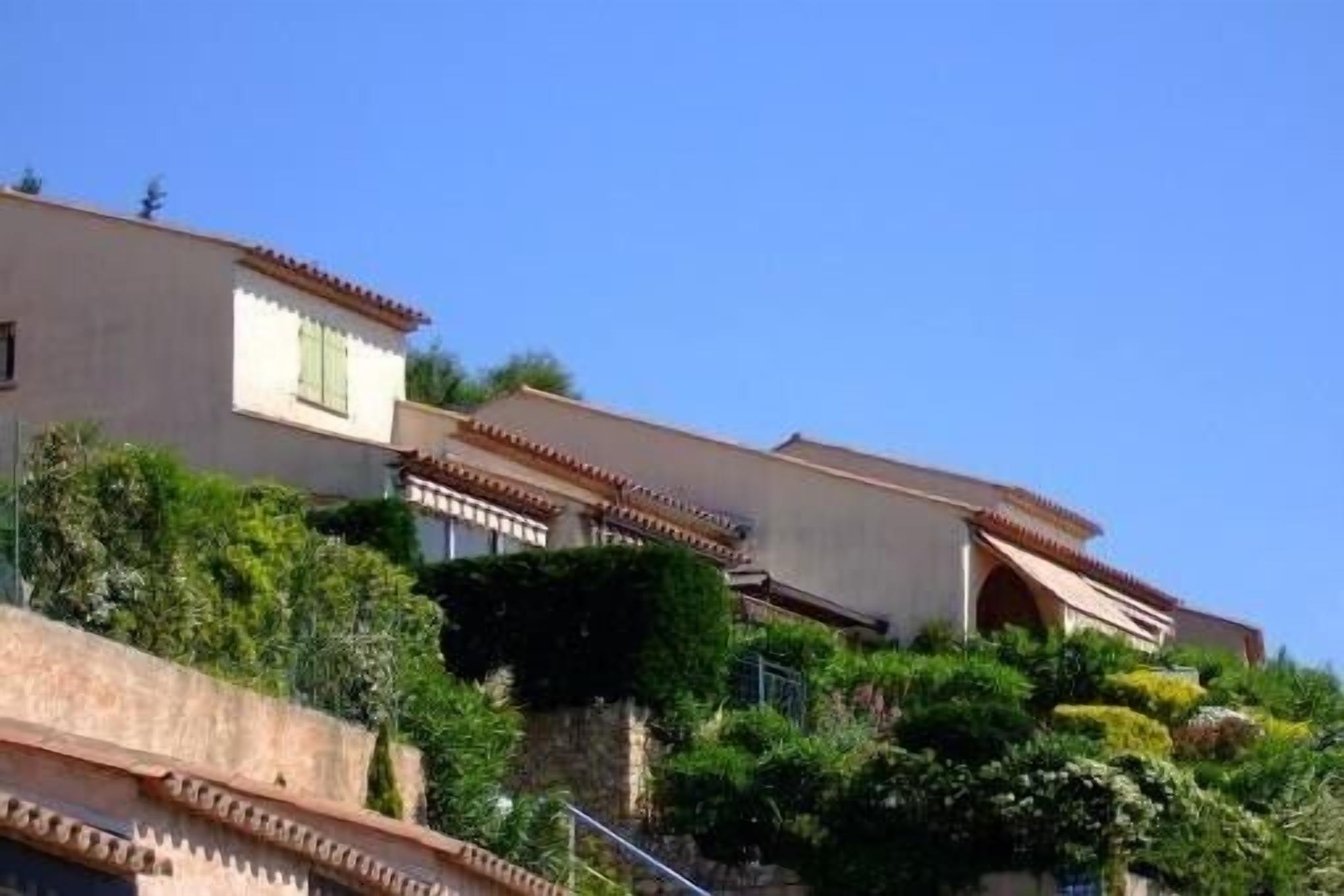 Un immeuble à plusieurs étages, doté d’une conception en terrasses, avec des balcons et une combinaison de toits plats et inclinés.