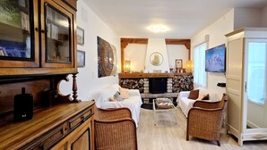 A cozy living room with a fireplace, wicker chairs, a coffee table, and a television.