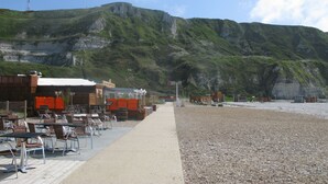 A coastal area with outdoor seating and a view of rocky cliffs.