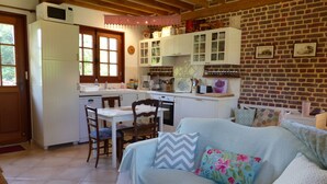 A cozy kitchen with white cabinets, a dining table, and a sofa with floral cushions.