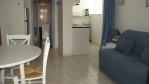 A compact living space with a dining area, kitchenette, and a sofa.