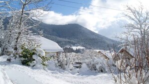 Un pueblo cubierto de nieve con casas tradicionales, una montaña al fondo y un cielo despejado.
