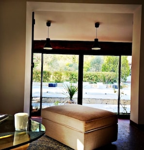 A modern room with a large window, a cushioned bench, and a glass table with a candle.