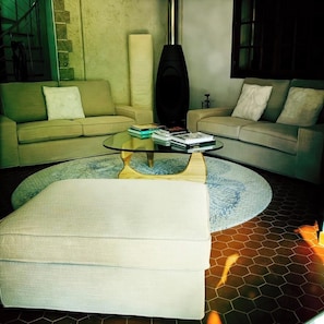 A modern living room with a glass coffee table, two sofas, and a hexagonal patterned floor.