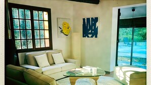 Una sala de estar con un sofá, una mesa de centro y un ventanal con vista a árboles.
