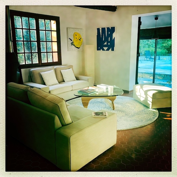 A living room with a sofa, a coffee table, and a large window with a view of trees.