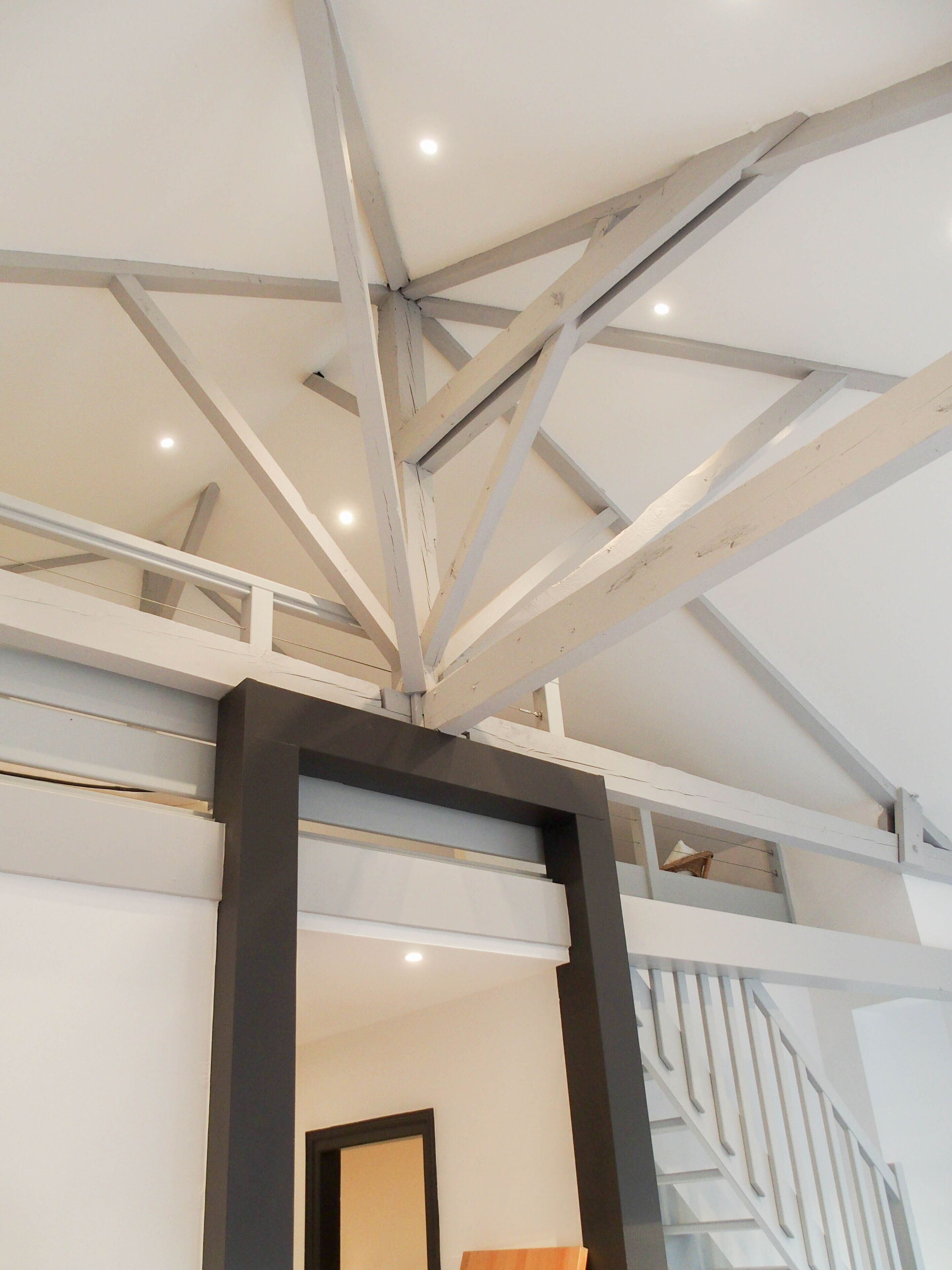 A high ceiling with exposed beams and a staircase.