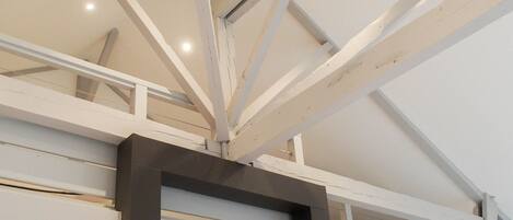 A high ceiling with exposed beams and a staircase.