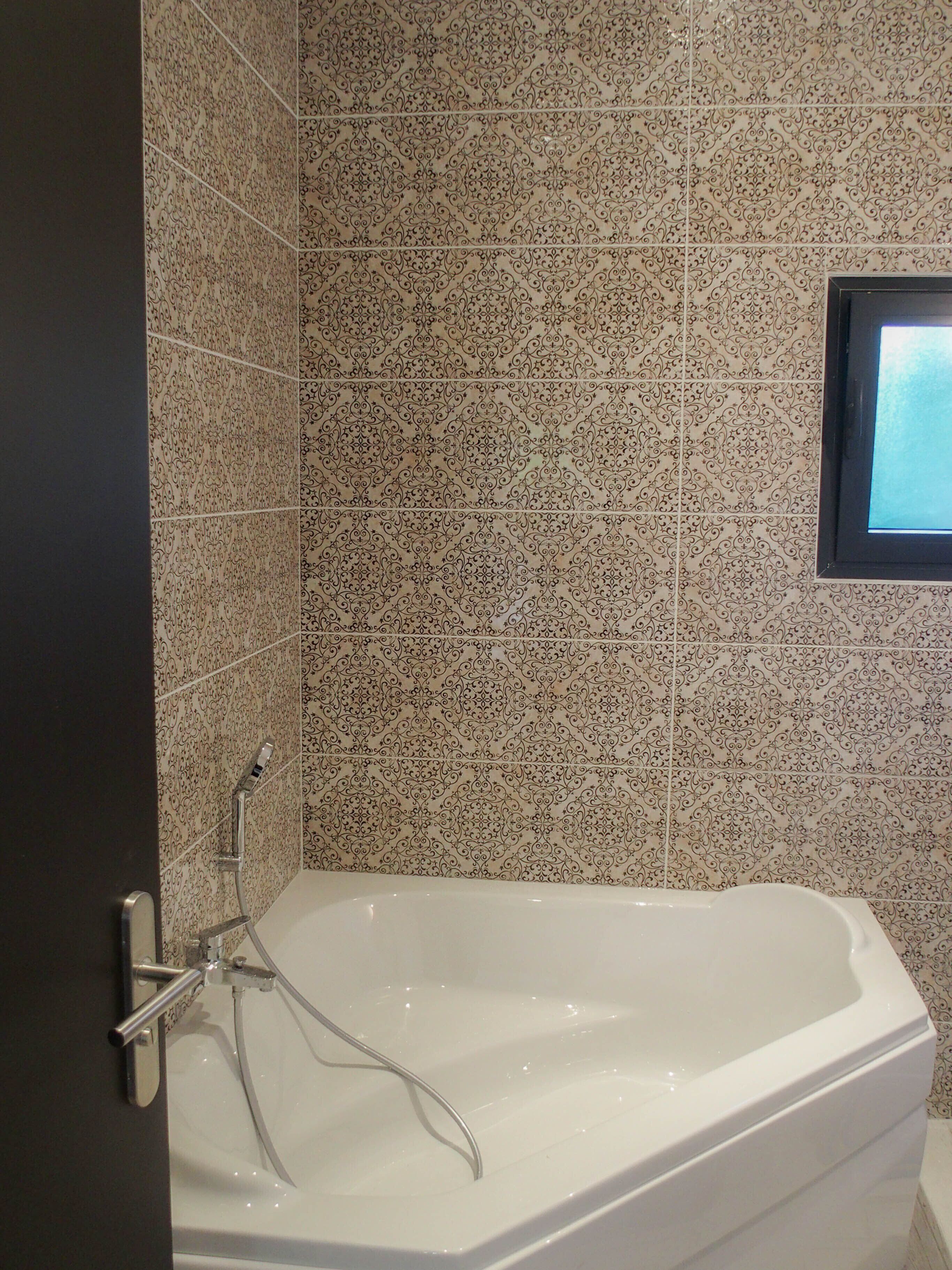 Ein Badezimmer mit einer freistehenden Badewanne, einer Duschbrause und einem kleinen Fenster.