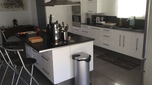 Een moderne keuken met witte kasten, een roestvrijstalen afzuigkap, een zwart aanrecht en een afvalbak.