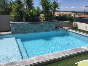 A rectangular swimming pool with clear blue water, surrounded by a stone wall and green plants. - The Magnificent "La Douceur de Vénus" Villa (Vendres)