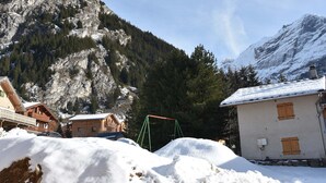 Un paysage de montagne avec une cabane en bois et un ensemble de balançoires au premier plan.