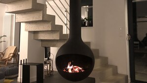 Ein modernes Interieur mit einem zentralen Kamin, einer Wendeltreppe und einem Kuhfellteppich.