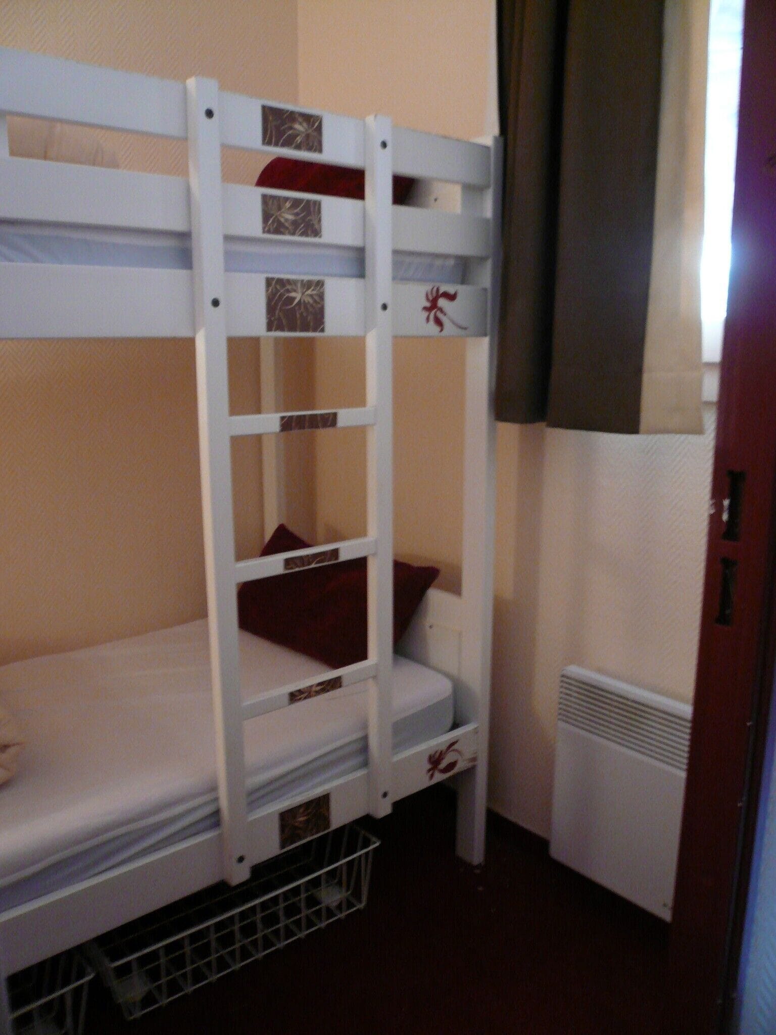 A bunk bed with a ladder, a radiator, and a door.