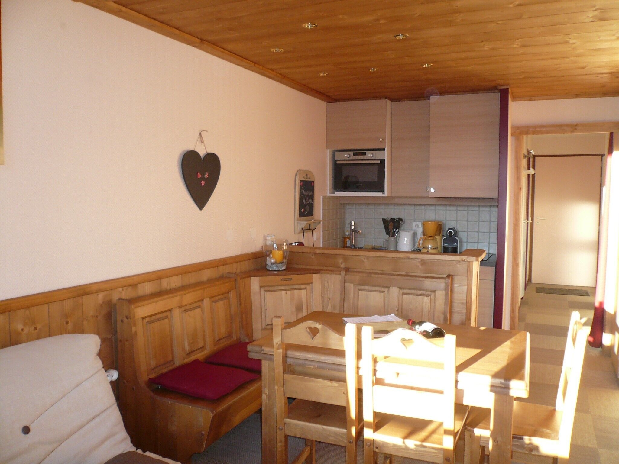 Una cocina acogedora con armarios de madera, una decoración con forma de corazón y un comedor con mesa y sillas.