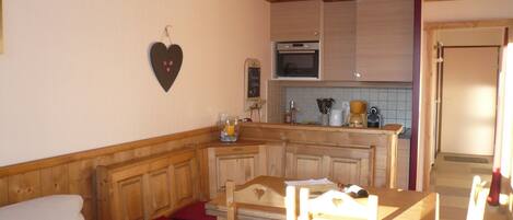 A cozy kitchen with wooden cabinets, a heart-shaped decoration, and a dining area with a table and chairs.