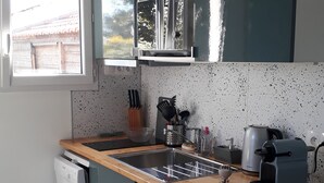 Eine kompakte Küche mit integriertem Geschirrspüler, einer Kaffeemaschine und einer Mikrowelle.