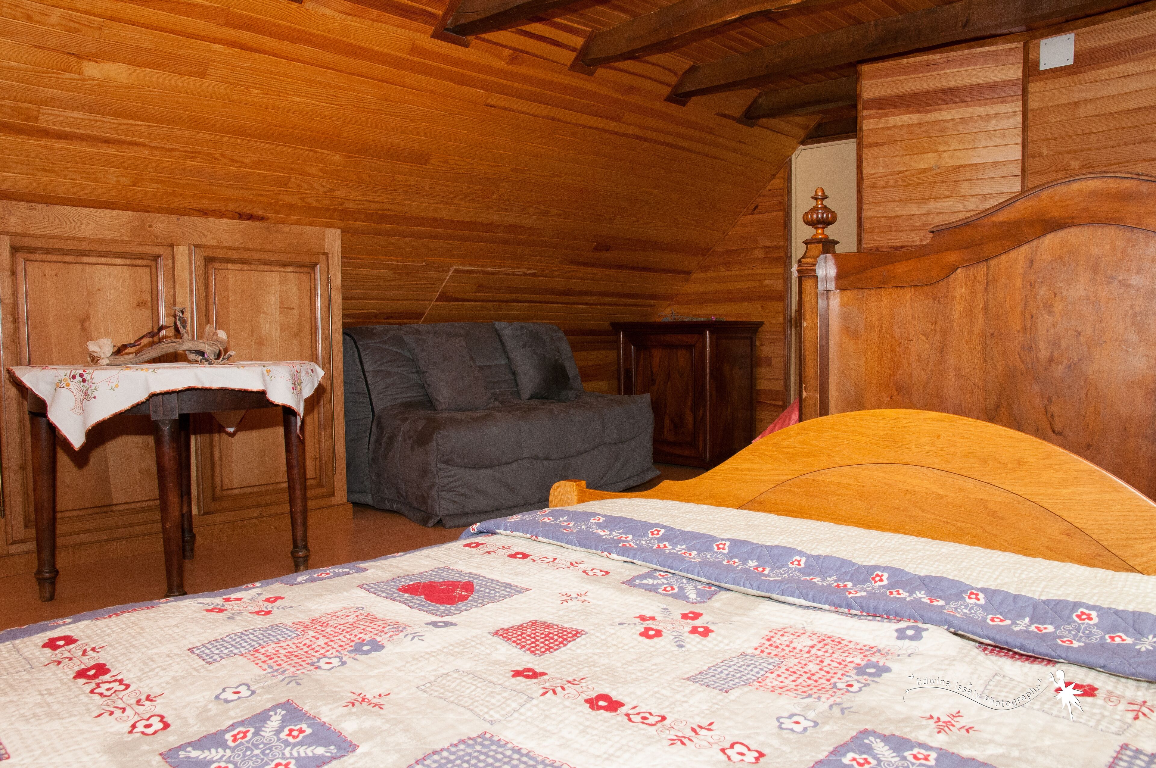 Een kamer met een houten vloer, een bed, een tafel en een stoel.