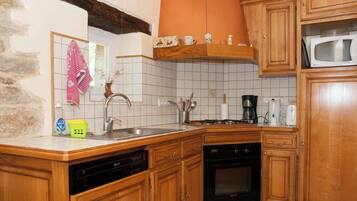 A kitchen with wooden cabinets, a dishwasher, an oven, and a microwave.
