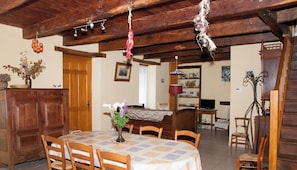 A dining area with a wooden table and chairs, a vase with flowers, and a wooden cabinet.