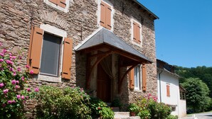 A stone building with a wooden porch, potted plants, and a clear blue sky.