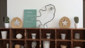 A shelf with various decorative items including a woven hat, star-shaped objects, and a framed text piece. - Sunny family home, 900m. from beach, equipped garden with a shower, WIFI HD, TV (Plurien)