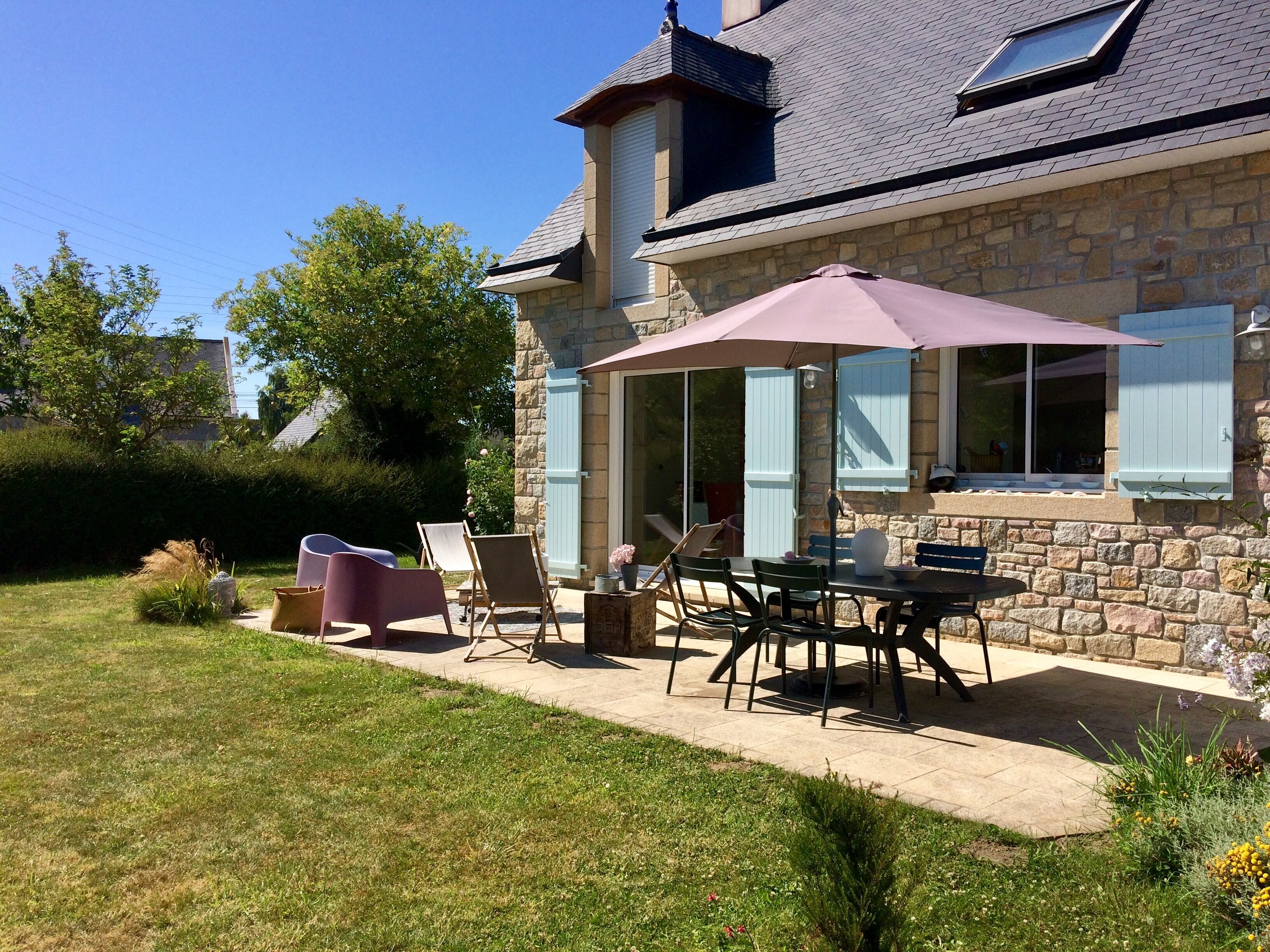 A stone house with a patio, outdoor seating, and a covered area.