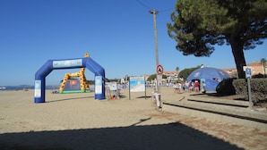 A beach entrance with a blue inflatable archway, a no parking sign, and a large tree. - Classified 2** T2 + cabin apartment facing the sea - Miramar beach - private parking (La Londe-Les-Maures)