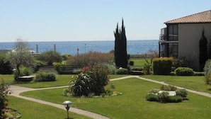 A well-maintained garden with a pathway leading to a building with a tiled roof. - Classified 2** T2 + cabin apartment facing the sea - Miramar beach - private parking (La Londe-Les-Maures)