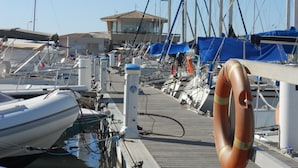 A marina with multiple boats docked, a lifebuoy attached to a dock, and a building in the background. - Classified 2** T2 + cabin apartment facing the sea - Miramar beach - private parking (La Londe-Les-Maures)