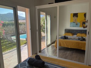 A bedroom with a bed, a painting, and a view of a pool and mountains. - Beautiful villa with private pool 200 metres from the beach  (Sainte lucie de Porto-Vecchio)