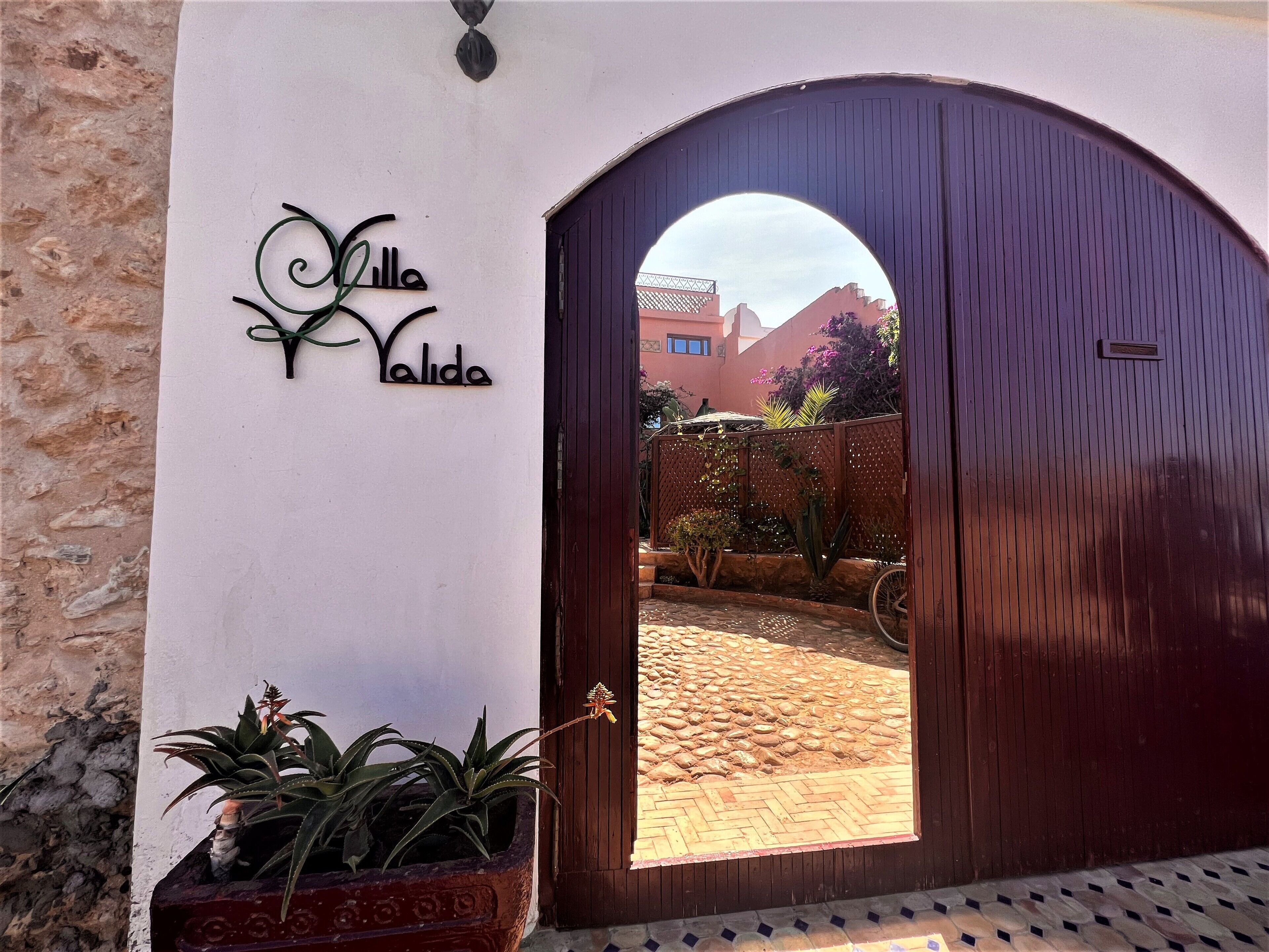 A hotel entrance with a wooden archway, a potted plant, and a sign with the name 'Villa Valida'.