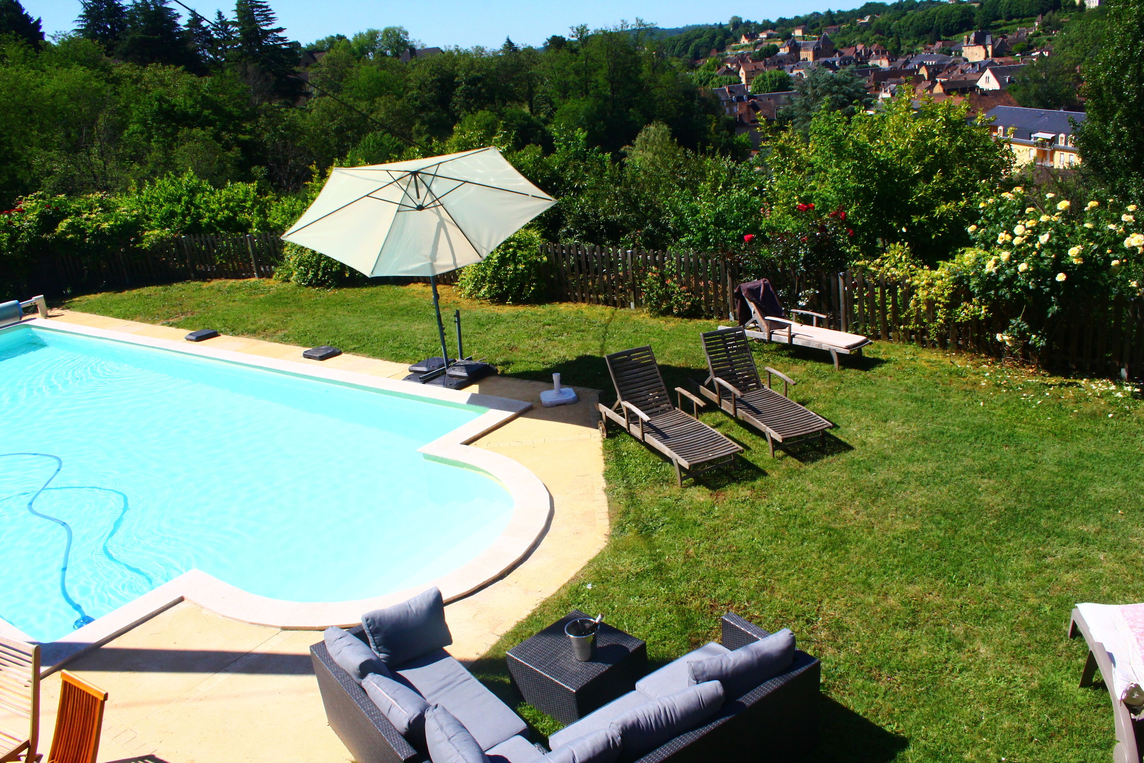 A backyard with a swimming pool, lounge chairs, and a patio umbrella.