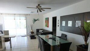 A modern dining area with a glass-top table, black chairs, a ceiling fan, and a large window with curtains. - Very beautiful wooded villa, heated swimming pool, breathtaking view - 8/10 people (Les Cluses)
