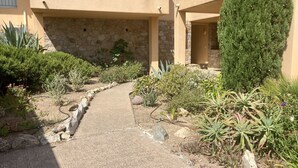 Un chemin menant à un bâtiment doté d’une façade en pierre et d’un balcon.
