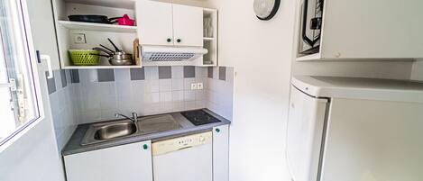A compact kitchen with a sink, stove, and dishwasher. There is a refrigerator and a window on the left side.