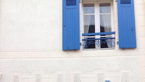 Un bâtiment à deux étages avec des volets bleus et une porte bleue.