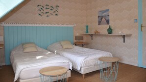 Une chambre avec deux lits, une petite table, une étagère avec des objets décoratifs et un mur orné d’une fresque représentant des poissons.
