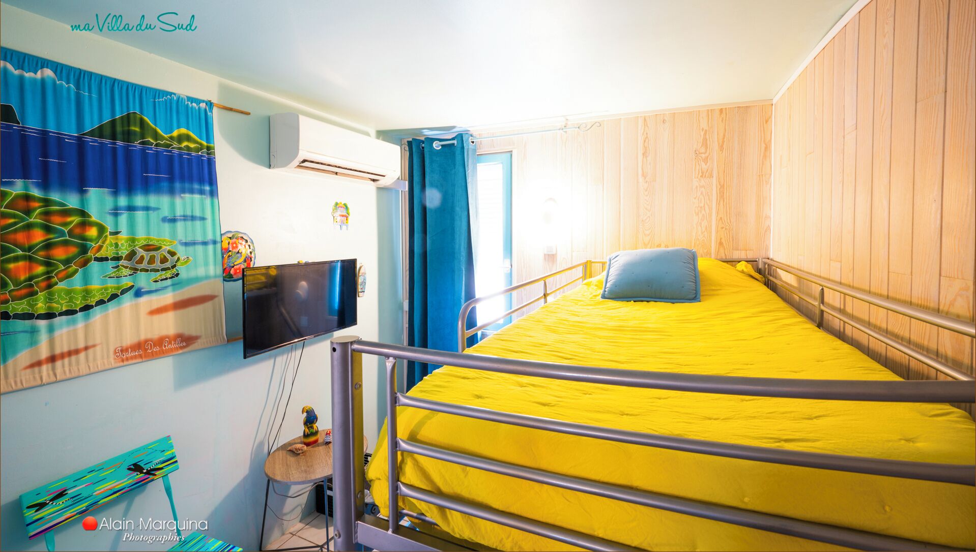 Una habitación con una cama, un televisor, una ventana y una pared con un mural.
