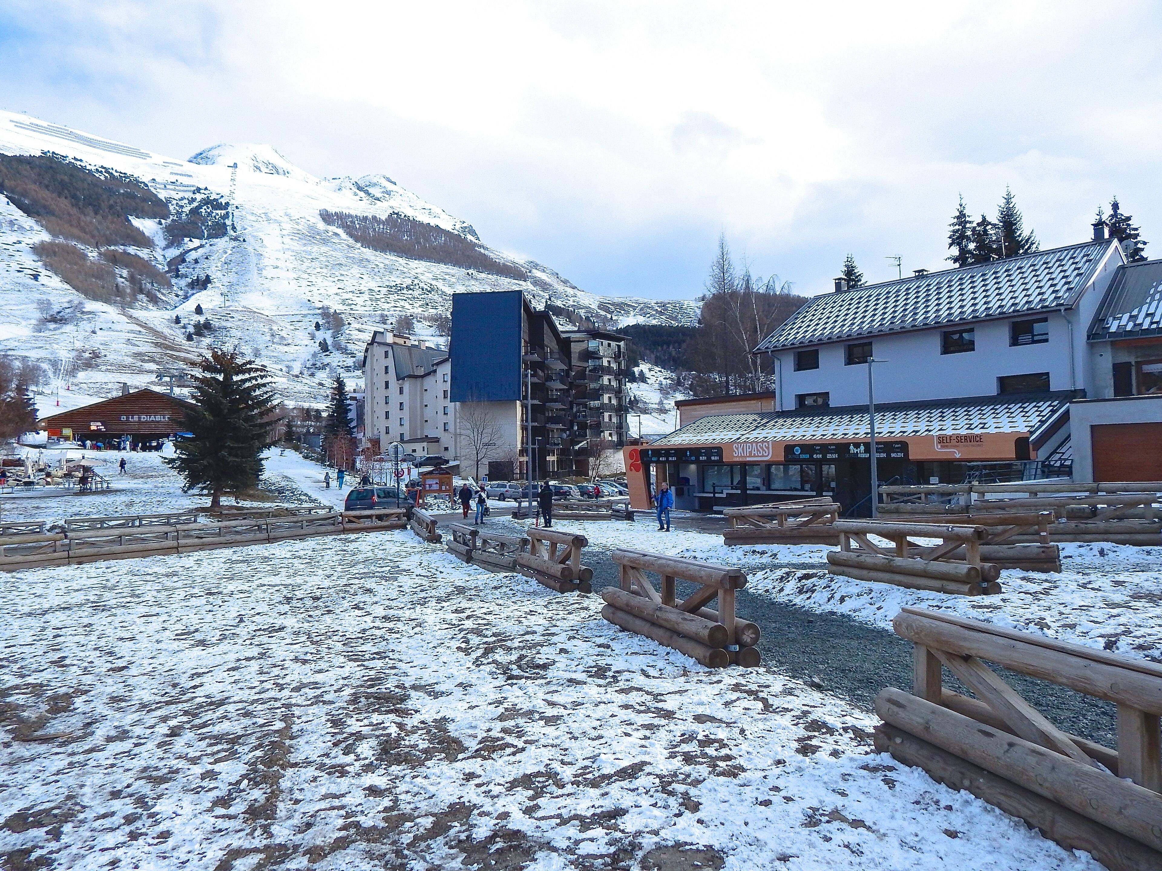 Un centro de esquí cubierto de nieve con edificios, vallas de madera y una montaña al fondo.