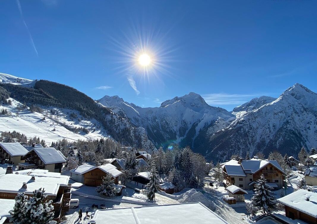 A snow-covered mountain village with wooden houses and a clear sky.