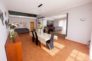 A spacious living area with a dining table, chairs, and a sofa.