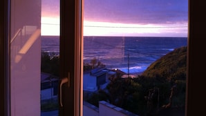 A view from a window overlooking a coastal area with houses and a hilly landscape.