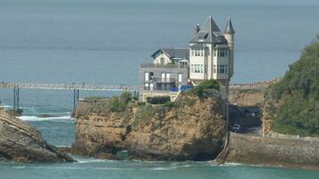 Une maison côtière dotée d’une tour imposante, située sur une falaise surplombant la mer.