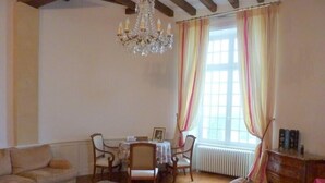 A living room with a sofa, armchairs, a coffee table, a chandelier, a dining table with chairs, and a window with curtains. - Château near the Puy du Fou, in the heart of the Vendée bocage (Sèvremont)