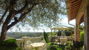 Un patio con mobiliario exterior, una pérgola y vistas a un paisaje montañoso.