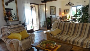 Una sala de estar con un sofá a rayas, un sillón con un cojín amarillo y una mesa con un tazón de comida.