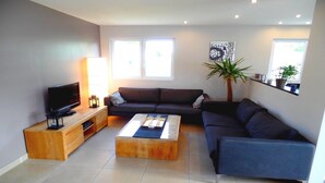 A living room with a TV, sofa, coffee table, and a plant.