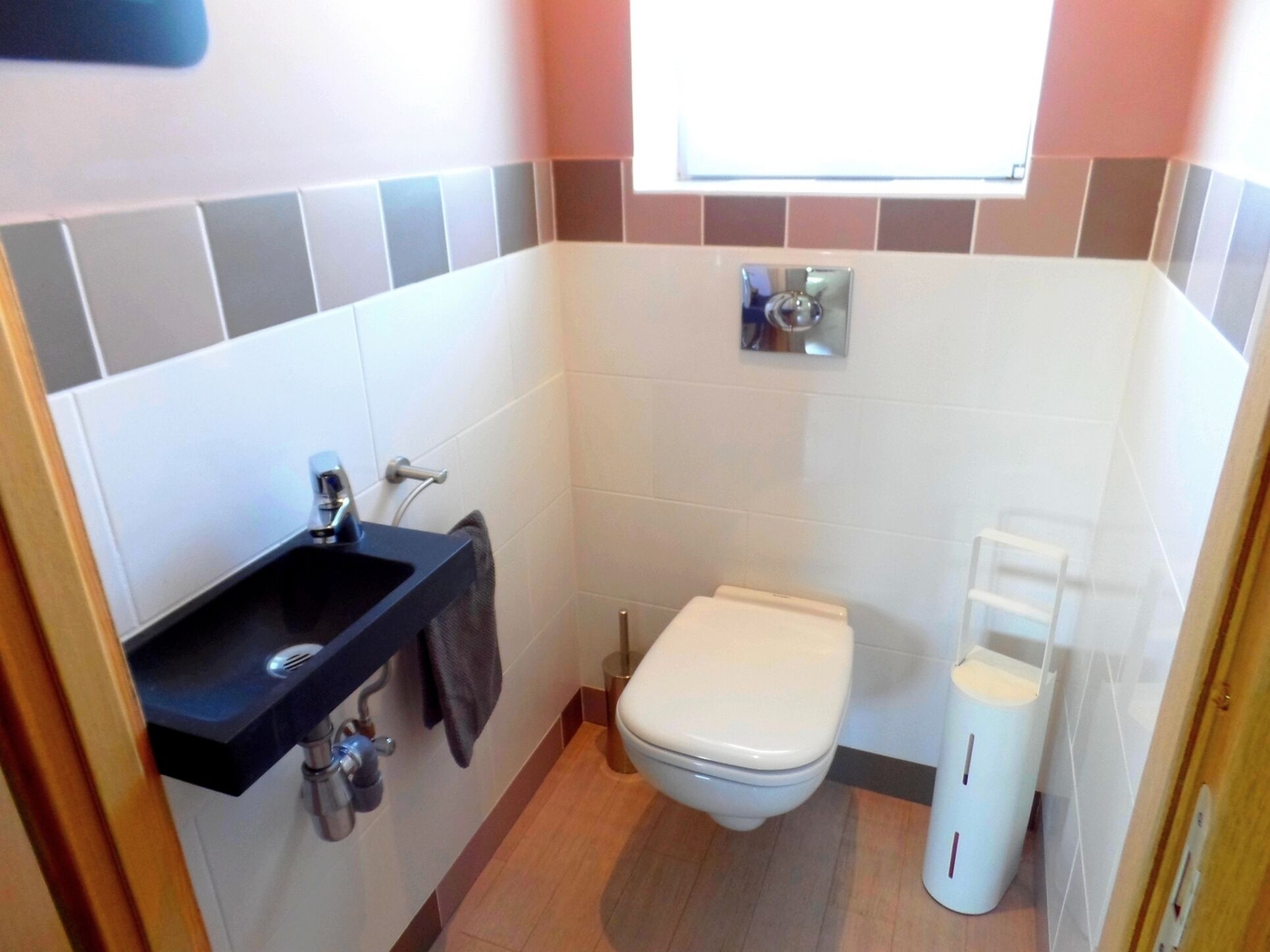 A small bathroom with a toilet, sink, and a window above the toilet.